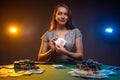 Attractive smiling woman siting at the table in casino and shows poker card. Lucky player on smoky background with lamps. Concept Royalty Free Stock Photo