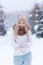 Attractive smiling young blonde girl walking in winter forest. Pretty woman in wintertime outdoor. Wearing winter clothes. Royalty Free Stock Photo