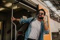 Attractive smiling young hispanic wearing sunglasses and blue shirt male holding smartphone hand and calling to friends