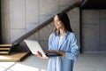 Attractive smiling young brunette woman using laptop computer while standing in a stylish living room Royalty Free Stock Photo