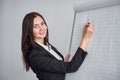 Beautiful smiling young woman writing on a blank flipchart in office as she does a presentation or promotion Royalty Free Stock Photo