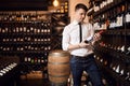 Attractive sommelier wearing white shirt and trousers standing in wine store