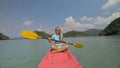 Sportive woman rows pink plastic canoe along sea water.