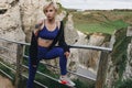 attractive sportswoman in stylish sportswear posing on cliff near railings Royalty Free Stock Photo