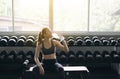 Attractive sporty woman sitting and drinking water in gym,Asian young female break and relex after workout
