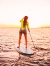 Attractive sporty woman stand up paddle surfing with beautiful sunset or sunrise colors Royalty Free Stock Photo