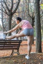 Attractive sporty woman warming up in a park. Beautiful girl doing warm-up exercises Royalty Free Stock Photo