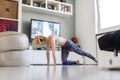 Attractive sporty woman working out at home, doing pilates exercise in front of television in her living room. Social Royalty Free Stock Photo