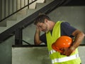 . Attractive stressed and frustrated construction worker man in vest and builder helmet looking tired and worried suffering
