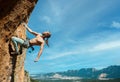 Attractive strong man looking up while climbing challenging route on height vertical rock. Amazing nature view on Royalty Free Stock Photo