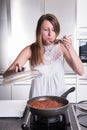 Attractive student cooking bolognese sauce in kitchen Royalty Free Stock Photo