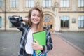 Attractive student girl with books and notebooks in his hands puts on a camera at the Royalty Free Stock Photo