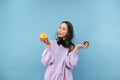 Attractive student girl in headphones around his neck stands on a blue background with apples in his hands