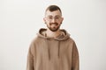 Attractive stylish alternative man with beard in trendy brown hoodie and flesh tunnels, smiling cheerfully, being glad Royalty Free Stock Photo