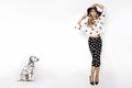 Attractive stylish blonde model in black and white clothes stand near  dalmatian dog. Beautiful fashion model, dressed in pinup Royalty Free Stock Photo