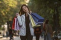 Attractive stylish brunette woman walks in the park with colorful shopping bags. Girl with purchases in her hands Royalty Free Stock Photo