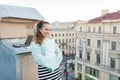 Attractive and stylish business woman holding a document and smiling while standing on the roof of the house in the Old town Royalty Free Stock Photo