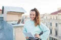 Attractive and stylish business woman holding a document and smiling while standing on the roof of the house in the Old town Royalty Free Stock Photo