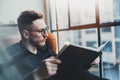 Attractive stylish businessman reading black book while sitting in vintage chair at his modern office.Young man relaxing Royalty Free Stock Photo