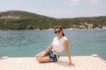 Attractive stylish woman on the pier by the sea. Beautiful inflow surrounded by mountains