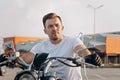 Attractive stylish young man in white T-shirt sits on a motorcycle. Portrait handsome biker posing on a bike. Life style Royalty Free Stock Photo