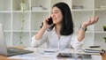 Successful Asian businesswoman at her office desk talking on the phone with her partner Royalty Free Stock Photo