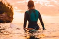 Attractive surf girl with perfect body on surfboard in ocean. Surfing at sunset