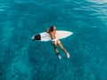 Attractive surfer woman relaxing on surfboard in ocean. Aerial view with surf girl