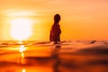 Attractive surfer woman on a surfboard in ocean. Surfgirl at sunset