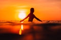 Attractive surfer woman on a surfboard in ocean. Surfgirl at sunset