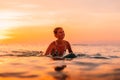 Attractive surfer woman on a surfboard in ocean. Surfgirl at sunset