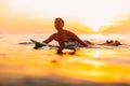 Attractive surfer woman on a surfboard in ocean. Surfgirl at sunset