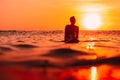 Attractive surfer woman on a surfboard in ocean. Surfgirl at sunset