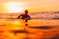 Attractive surfer woman on a surfboard in ocean. Surfgirl at sunset