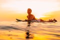 Attractive surfer woman on a surfboard in ocean. Surfgirl at sunset