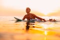 Attractive surfer woman on a surfboard in ocean. Surfgirl at sunset