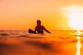 Attractive surfer woman on a surfboard in ocean. Surfgirl at sunset