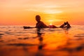 Attractive surfer woman on a surfboard in ocean. Surfgirl at sunset