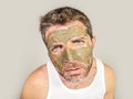 Attractive and surprised funny man horrified looking himself on bathroom mirror ugly and weird applying green cream on his face i Royalty Free Stock Photo