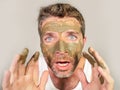 Attractive and surprised funny man horrified looking himself on bathroom mirror ugly and weird applying green cream on his face i Royalty Free Stock Photo