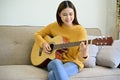 Attractive and talented Asian female practicing her guitar skills in her living room Royalty Free Stock Photo