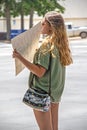 Attractive tanned woman in short shorts and sunglasses with long brunette hair and cute purse stands by