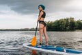 attractive tattooed woman with blue hair standup paddleboarding