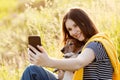 An attractive teen girl takes photos of herself and her dog using a mobile phone camera. A girl takes a photo while walking with Royalty Free Stock Photo