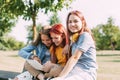 Attractive teenage girls are sitting on a park bench, discussing and smiling. Girlfriends are chatting in the park Royalty Free Stock Photo