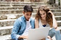 Teenage students with laptop sitting on stone steps. Royalty Free Stock Photo