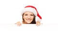 Attractive teenager girl in a Christmas hat with a blank billboard