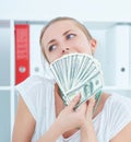 Attractive thinking happy woman holding dollars in hands and want to spend money. Royalty Free Stock Photo