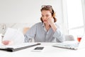 Attractive thinking woman in striped shirt holding her cheek while siting and reading contract at home Royalty Free Stock Photo