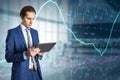 Attractive thoughtful caucasian businessman with tablet and abstract glowing forex graph standing on blurry office interior Royalty Free Stock Photo